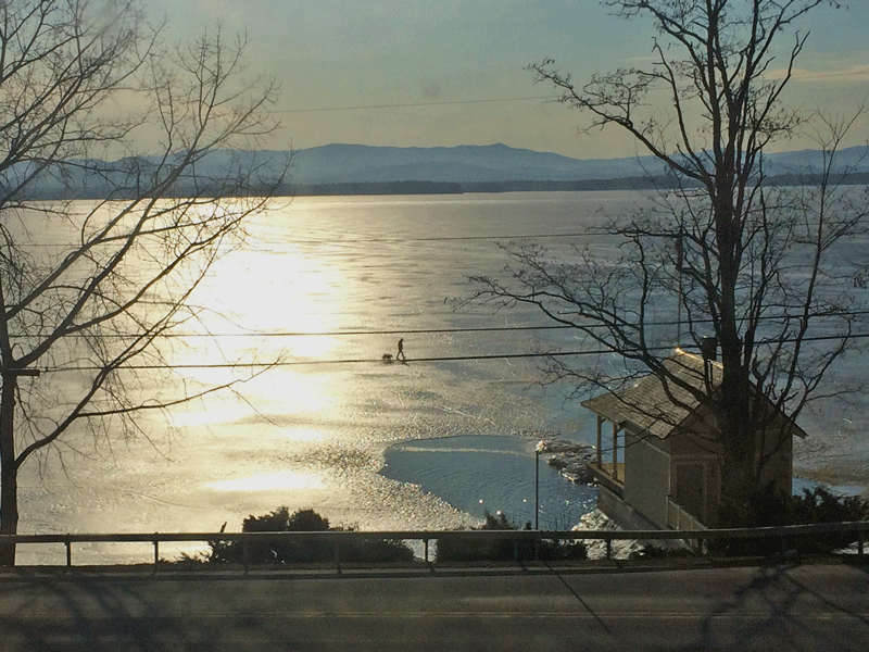 Photograph of Essex artist Bill Amadon (and his dog) walking/photographing on frozen Lake Champlain.